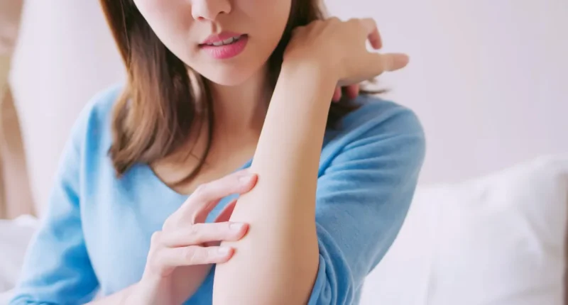 Woman scratching her arm, showing signs of dry and itchy skin even after using moisturizer, indicating the need for a more effective skincare routine.
