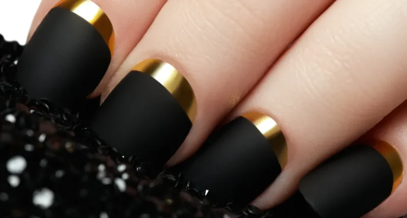 Close-up of elegant matte black nails with luxurious gold undersides, offering a striking contrast and sophisticated style for a celebratory occasion.