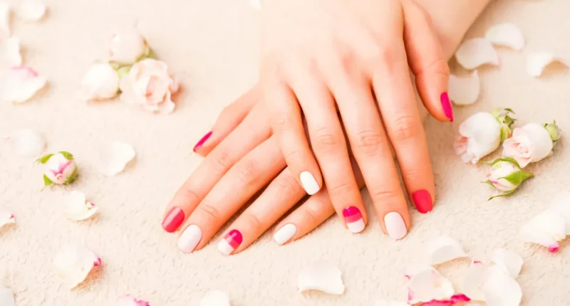 Romantic nail design with a mix of solid pink, white, and floral patterned nails, surrounded by soft rose petals for a Valentine's ambiance.